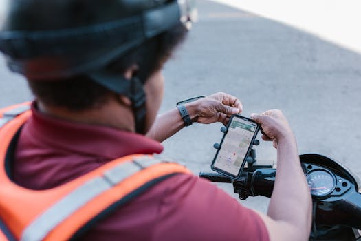 A delivery rider checks directions on a smartphone mounted on a scooter outdoors.