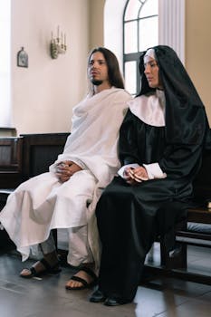 Nun and man depicting religious figures sitting indoors in a church setting, illustrating devotion.