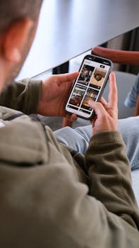 Casual man using a smartphone with photo gallery app indoors.